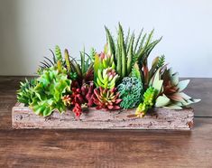 an arrangement of succulents and other plants in a wooden box on a table