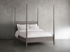 a bed with four posts and white sheets in a gray room, against a concrete wall