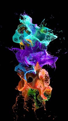 colorful ink is mixed in with water on a black background