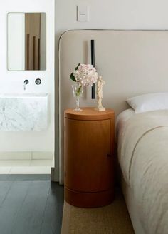 a bedroom with a bed, nightstand and mirror on the wall next to a sink