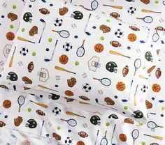 the bedding is made up with sports related items on it, including tennis balls and racquets