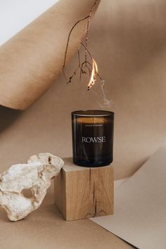 a candle sitting on top of a wooden block next to a white rock and twig