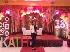 a woman sitting on top of a stage surrounded by flowers and balloons in front of her