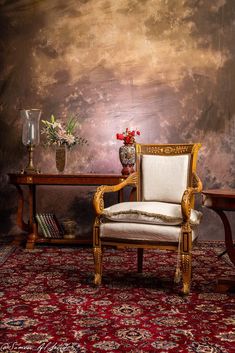 a chair sitting on top of a red rug next to a table with vases and flowers