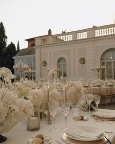 the table is set with white flowers and place settings for an elegant dinner or reception