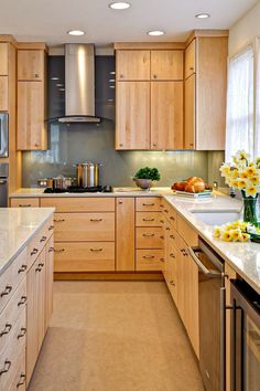 a kitchen filled with lots of wooden cabinets and counter top space next to a window