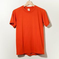 70s Vintage Single Stitch Blank T-Shirt Made in USA Burnt Orange SmallMeasurements: Chest (Pit To Pit) : 16.5" x Length : 23.5"  (Center Back Neck to Hem)Distressed Minimal 80s Retro Hanes Sears Levi's Work Wear RRL CGD Jc Penny*PLEASE BE AWARE THESE ITEMS ARE VINTAGE AND SHOW SIGNS OF WEAR. *There may be small stains and minor imperfections that are not stated. *USE ZOOM FOR DETAILS. Cheap Retro Orange T-shirt, Affordable Orange Retro T-shirt, Retro Orange Crew Neck T-shirt, Vintage Short Sleeve T-shirt, Orange Retro Crew Neck T-shirt, Retro Orange Cotton T-shirt, Vintage Orange Short Sleeve T-shirt, Vintage Solid Color Cotton T-shirt, Retro Crew Neck Solid Tops