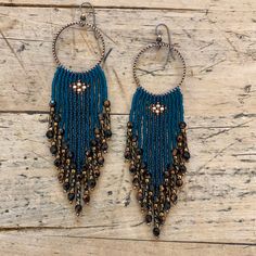 a pair of blue beaded earrings on top of a wooden table