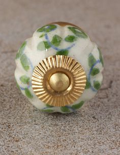 a white and green flowered knob with gold trim