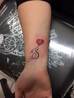 a woman's arm with a tattoo on it and a red heart in the middle