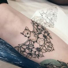 a woman's thigh with flowers and a cat on it