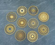 nine circular metal pieces on a blue surface, each with an intricate design in the middle