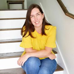 a woman sitting on some stairs smiling for the camera