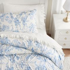 a blue and white comforter with ruffled edges on a bed in a bedroom