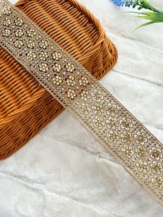 a close up of a ribbon on a table with flowers in the background and a basket next to it