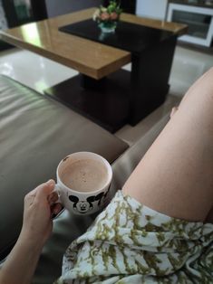 a person sitting on a couch holding a coffee cup