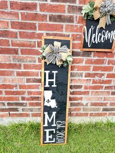 a welcome home sign next to a brick wall with wreaths on the front and back