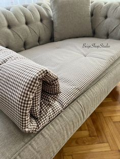 a couch that is sitting on top of a hard wood floor with a checkered blanket