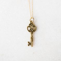 a gold key necklace on a white surface