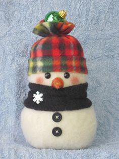 a small snowman with a hat and scarf on it's head is sitting on a blue blanket