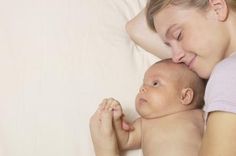 a woman laying down next to a baby