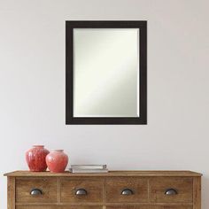 a wooden dresser sitting next to a mirror on top of a wall with two vases