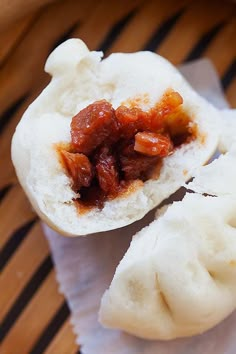 two dumplings with meat and sauce sitting on top of a paper towel in a basket