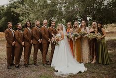 a group of people standing next to each other in front of some trees and grass