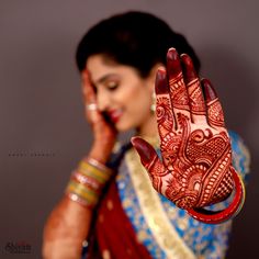 a woman holding her hand up to her face with henna painted on it's palm