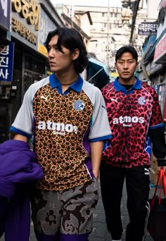 two men are walking down the street in their colorful outfits and one is carrying a handbag