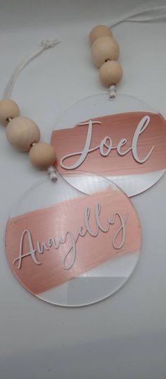 two pink and white wooden name tags hanging from a string