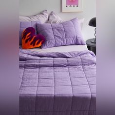 a bed with purple comforter and pillows on it