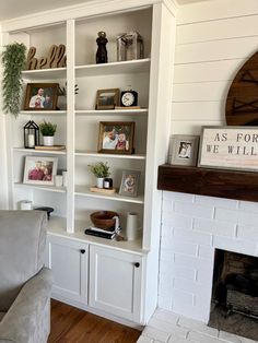 a living room with white bookcases and pictures on the wall above it, along with a fireplace