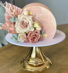 there is a pink hat with flowers on top of the cake platter that has gold trim around it