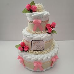 a three tiered cake decorated with pink roses and diaper on the bottom layer