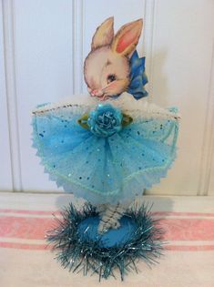 a small figurine is dressed in blue and white with a rabbit on it's head