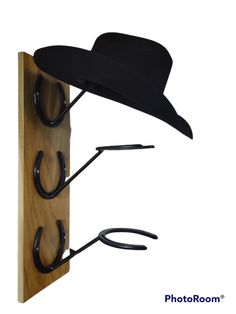 a hat and two pairs of scissors hanging on a wooden board with hooks attached to it