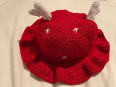 a red crocheted hat with antlers on it's brim sits on top of a white sheet