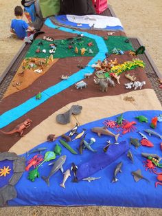 children are playing with their toys on the sand in front of a play mat that is made to look like an ocean scene