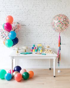 a party table with balloons and confetti on it