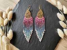 Statement earrings with long ombre fringes and detailed brass findings Color: brass with pink to light blue color gradient These large fringe earrings stand out immediately because of their finely worked brass findings and long ombre fringes. The color gradient is an irregular pattern which results in a more natural looking color transition and less like a structured color scheme. In addition differently colored beads were used to add more details to the fringe - either as little dots, embellish Pink Fringe Earrings For Festival, Handmade Pink Tassel Earrings For Festival, Pink Handmade Tassel Earrings For Festivals, Pink Handmade Chandelier Earrings For Festivals, Handmade Pink Chandelier Earrings For Festivals, Bohemian Pink Chandelier Earrings For Festival, Blue Color Gradient, Ombre Fringe Earrings, Light Blue Shades