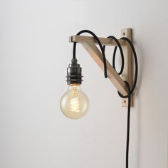 a light that is on the wall next to a black cord and a white wall