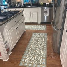 a kitchen with wooden floors and white cabinets, an area rug is on the floor