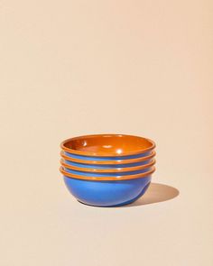 four blue and orange bowls stacked on top of each other in front of a white wall