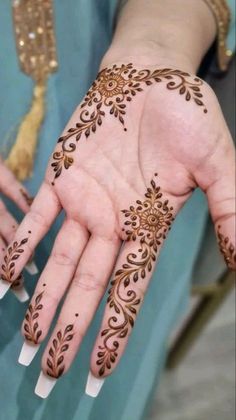 a woman's hand with henna tattoos on it and her hands in the shape of flowers