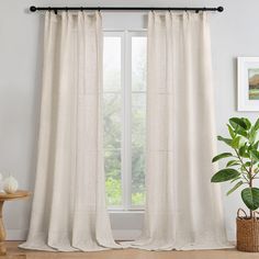 a living room with white curtains and a potted plant