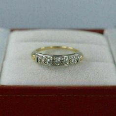 a gold ring with five diamonds in it sitting on top of a red velvet box