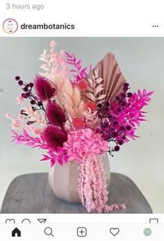 a vase filled with pink and purple flowers on top of a wooden table next to an instagram post