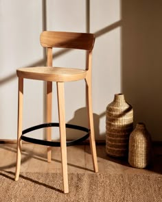 a wooden chair sitting on top of a brown rug next to a vase and basket