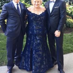 two men and a woman in formal wear standing next to each other on a sidewalk